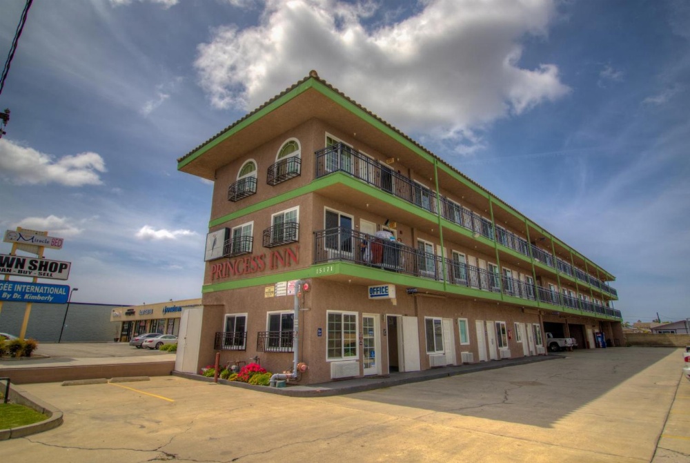 A three-story building with balconies and a parking lot