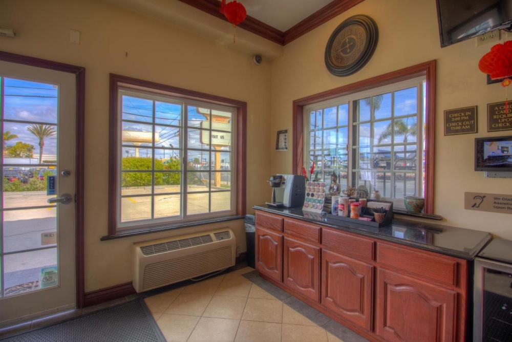 A hotel lobby with a counter, coffee machine, and windows.